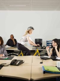 A girl cycles through an office
