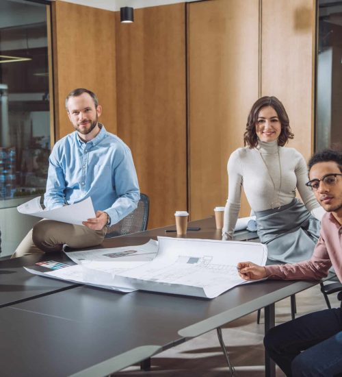 group of successful architects sitting at conference hall of office and looking at camera