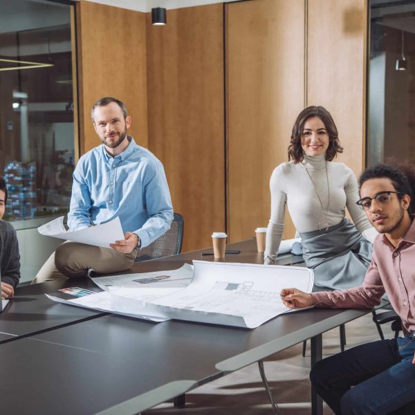 group of successful architects sitting at conference hall of office and looking at camera